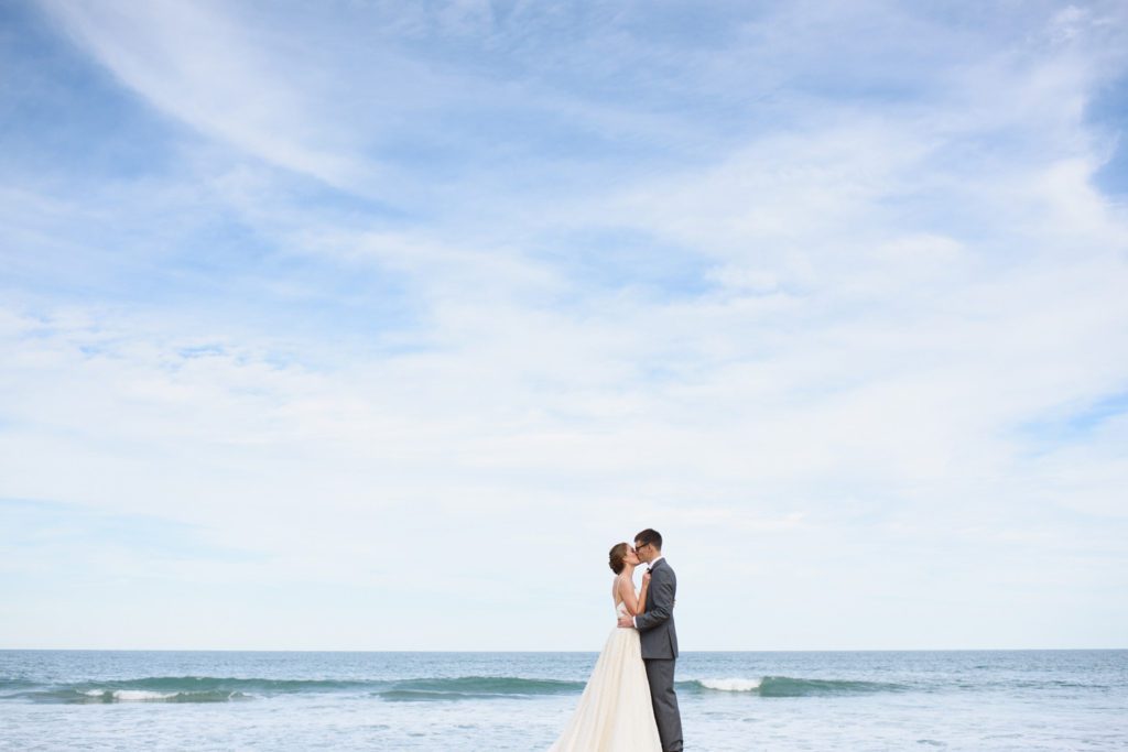 Bride and groom kiss by the ocean on the Outer Banks