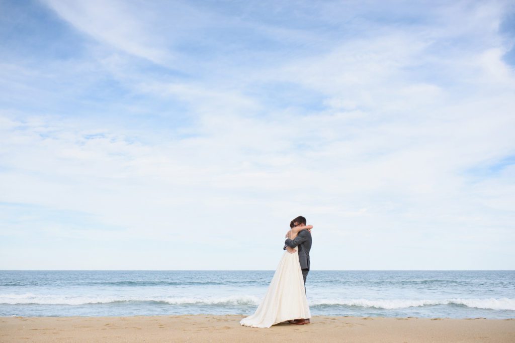 Bride and groom hug by the ocean on the Outer Banks