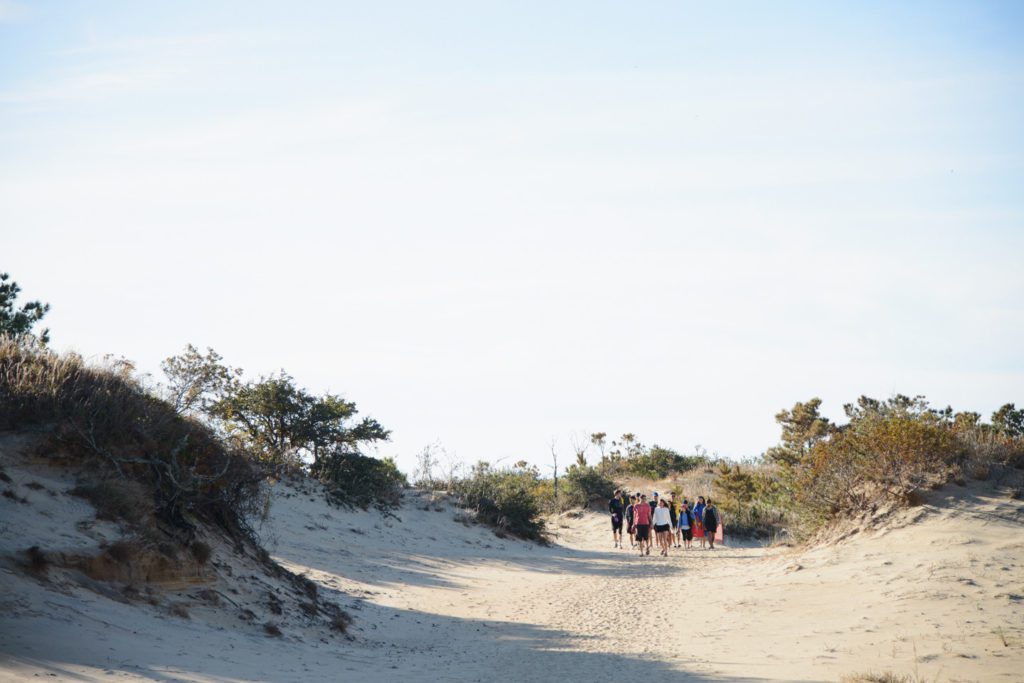Group of friends walking to play frisbee at Jockey's Ridge state park