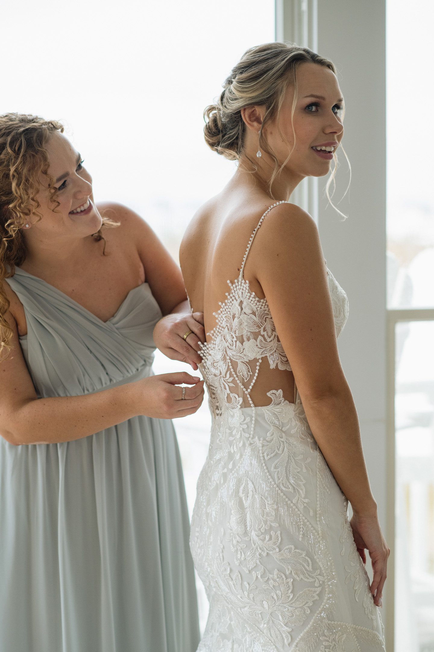 Maid of honor helping bride into her wedding dress